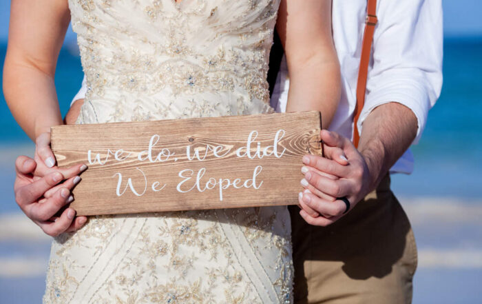 Bride and groom carrying a wooden sign saying “we eloped” at an elopement wedding